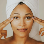 Mulher negra de toalha na cabeça mostrando sua pele após utilizar produto com colágeno biomimético